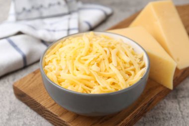 Gri masada rendelenmiş peynir parçaları, yakın plan.