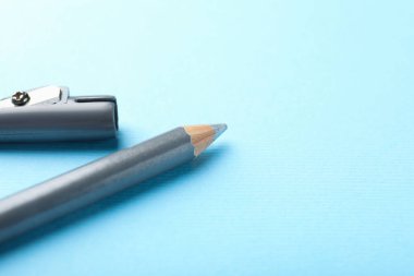 Açık mavi arka planda göz kalemi ve keskinleştirici, yakın plan. Metin için boşluk