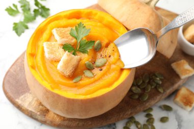 Beyaz masadaki balkabağı kremalı çorbayı içiyorum.