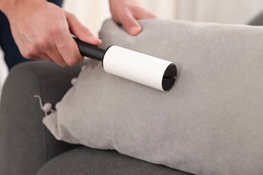 Evdeki kanepede pamuklu bezle yastığı temizleyen adam, yakın plan.