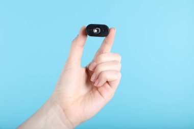 Açık mavi arka planda gizli casus kamerası olan kadın, yakın plan.