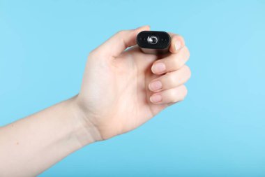 Açık mavi arka planda gizli casus kamerası olan kadın, yakın plan.