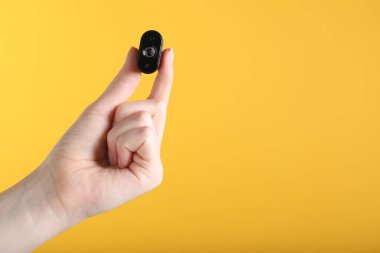 Sarı arka planda gizli casus kamerası olan kadın, yakın plan. Metin için boşluk