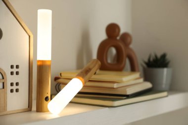 Portatif LED lambalar, kitaplar ve dekorlar beyaz rafta, yakın plan