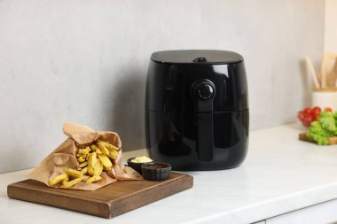 Kızartma makinesi, patates kızartması, soslar ve sebzeler beyaz mermer tezgahta.