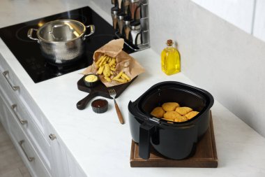 Tavuklu kızartma sepeti, patates kızartması, soslar ve baharatlar beyaz mermer tezgahta.