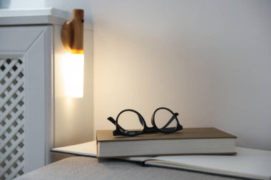 Puf gözlüklü kitaplar ve evdeki portatif LED lamba. Metin için boşluk