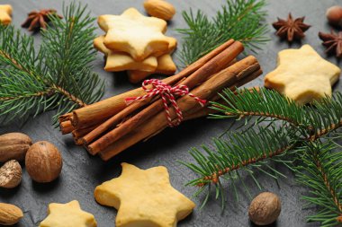 Noel kompozisyonu köknar ağacı dalları, kurabiyeler ve baharatlar siyah masada, yakın plan