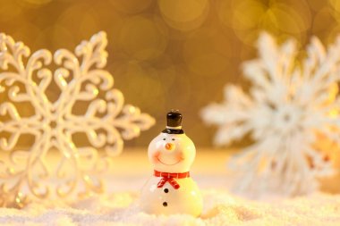 Tatlı dekoratif kardan adam ve kar taneleri suni kar üzerinde bulanık arka plana karşı, yakın plan