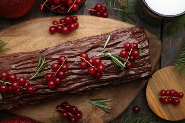 Lezzetli Noel kütüğü (geleneksel Noel pastası) ahşap masa üzerinde kırmızı frenk üzümü, düz yatar