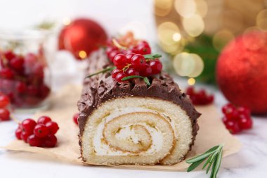 Lezzetli Noel kütüğü (geleneksel Noel pastası) kırmızı frenk üzümü ve dekorlu beyaz masa, yakın plan