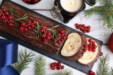 Lezzetli Noel kütüğü (geleneksel Noel pastası) kırmızı frenk üzümü, dekor ve köknar ağacı dalları açık ahşap masa üzerinde, düz yatıyordu
