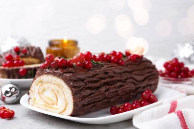 Lezzetli Noel kütüğü (geleneksel Noel pastası) gri desenli masa üzerinde kırmızı frenk üzümü, yakın plan