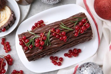 Lezzetli Noel kütüğü (geleneksel Noel pastası) kırmızı frenk üzümü ve dekorlu gri masa, düz yatıyordu