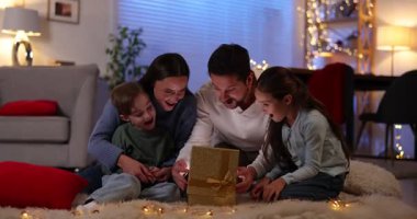 Mutlu bir aile sihirli Noel hediyesiyle yerde süslenmiş bir odada