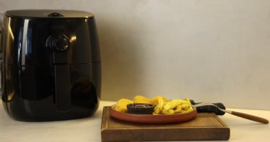 Kızarmış patates kızartması, tavuk nugget, sos ve hava fritözü beyaz mermer tezgahta, yakın plan. Kamera içeri giriyor.