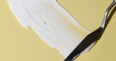 Bej arka planda spatula ile kozmetik ürünü karalamak, yakın plan