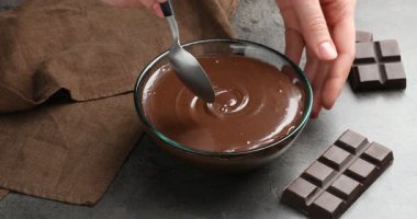 Gri masada erimiş çikolatayı karıştıran kadın, yakın plan.