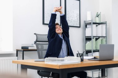 Genç işadamı kollarını uzatıp, masada oturuyor.