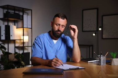 Doktor, gece vardiyası sırasında klinikteki masada notlar yazıyor.