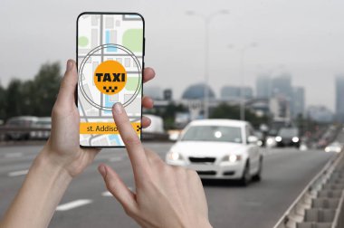 Şehir caddesinde taksi çağırmak için cep telefonu uygulaması kullanan bir adam.