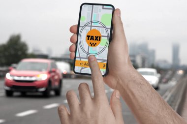 Şehir caddesinde taksi çağırmak için cep telefonu uygulaması kullanan bir adam.