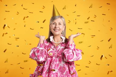 Mutlu yaşlı kadın ve sarı arka planda uçan konfeti