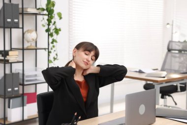 Genç iş kadını ofiste boynunu uzatıyor.