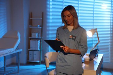 Doktor gece vardiyası sırasında klinikte notlar yazıyor. Metin için boşluk