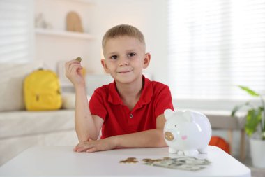Cep harçlığı ve kumbarası olan küçük bir çocuk.