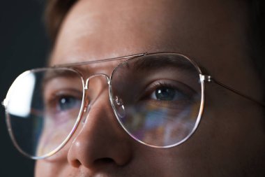 Karanlık arka planda yansıması olan gözlüklü bir adam, yakın plan.