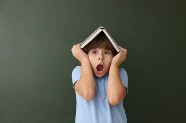 Okula dönelim. Kapalı alanda tahtaya karşı kitap yazan bir çocuk.