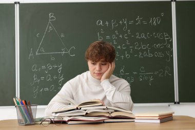 Okula dönelim. Tahta masada matematik ödevi ile çalışan öğrenci.