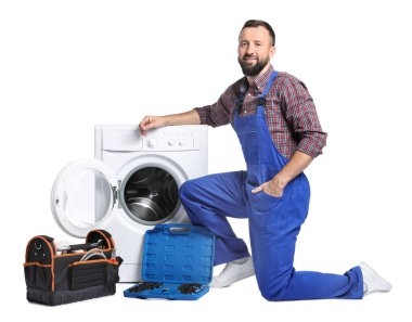 Beyaz arka planda bozuk çamaşır makinesinin yanında alet çantası olan profesyonel bir tamirci.