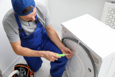 Profesyonel tamirci içeride bozuk çamaşır makinesini tamir ediyor.