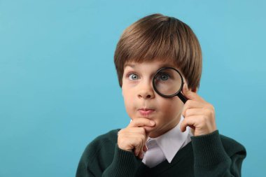 Açık mavi arka planda büyüteç takan küçük bir çocuk. Metin için boşluk