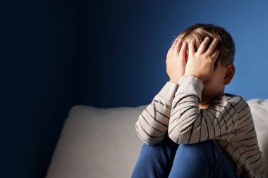 Üzgün küçük çocuk kanepenin içinde oturuyor, mesaj için yer var.