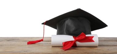 Mezuniyet şapkası ve diploması beyaz arka plana karşı ahşap masada.