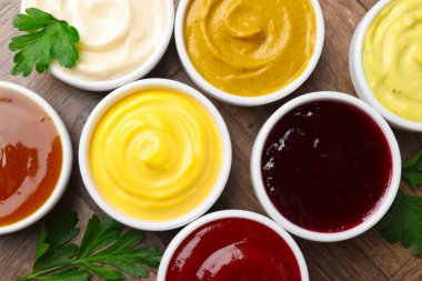 Tabaklardaki farklı lezzetli soslar ve ahşap masadaki maydanozlar.