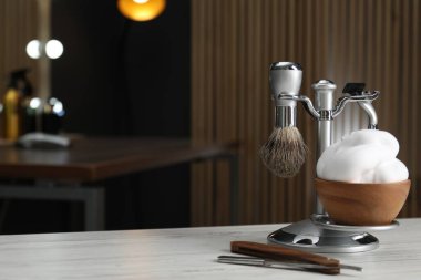 Berber dükkanında tıraş fırçası, tıraş bıçağı ve bir kase köpükle ahşap masa. Metin için boşluk
