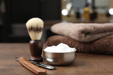 Traş fırçası, köpük, jilet ve havlular berber dükkanında ahşap masa, yakın plan.