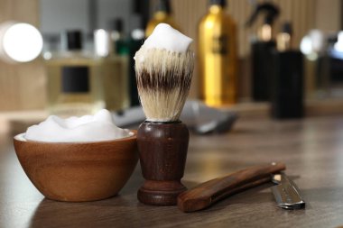 Traş fırçası, köpük ve jilet berber dükkanındaki ahşap masada, yakın plan.