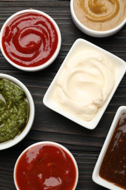 Tabaklardaki farklı soslar ahşap masada, düz yerde.