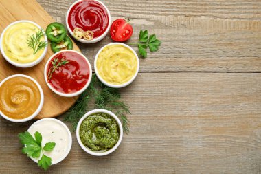 Farklı soslar ve otlar ahşap masada, düz yerde. Metin için boşluk