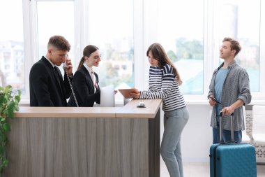 Otel resepsiyonunda misafirlerle çalışan resepsiyonist ve hostes.