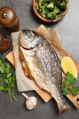 Lezzetli ızgara balık, brokoli ve baharat gri masada.