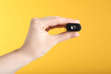 Sarı arka planda gizli casus kamerası olan kadın, yakın plan.