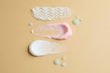 Bej arka planda farklı kozmetik ürünleri örnekleri, düz yatıyordu