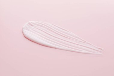 Pembe arka planda nemlendirici krem örneği, yakın plan.