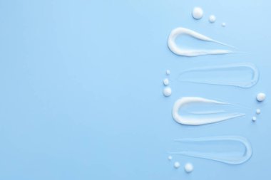 Açık mavi arka planda farklı kozmetik ürünlerinin örnekleri, düz. Metin için boşluk